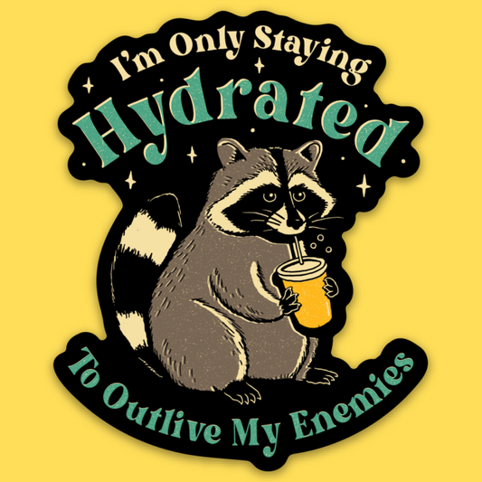 Vinyl sticker of a raccoon drinking from a yellow cup with text 'I'm Only Staying Hydrated to Outlive My Enemies' on yellow