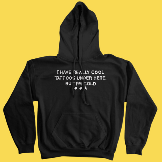Black graphic hoodie with white text reading 'I have really cool tattoos under here, but I'm cold' and three stars on yellow