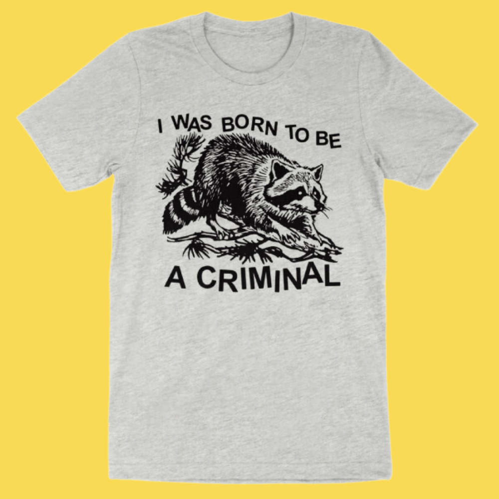 Heather gray t-shirt with black graphic of a raccoon and text 'I WAS BORN TO BE A CRIMINAL'
