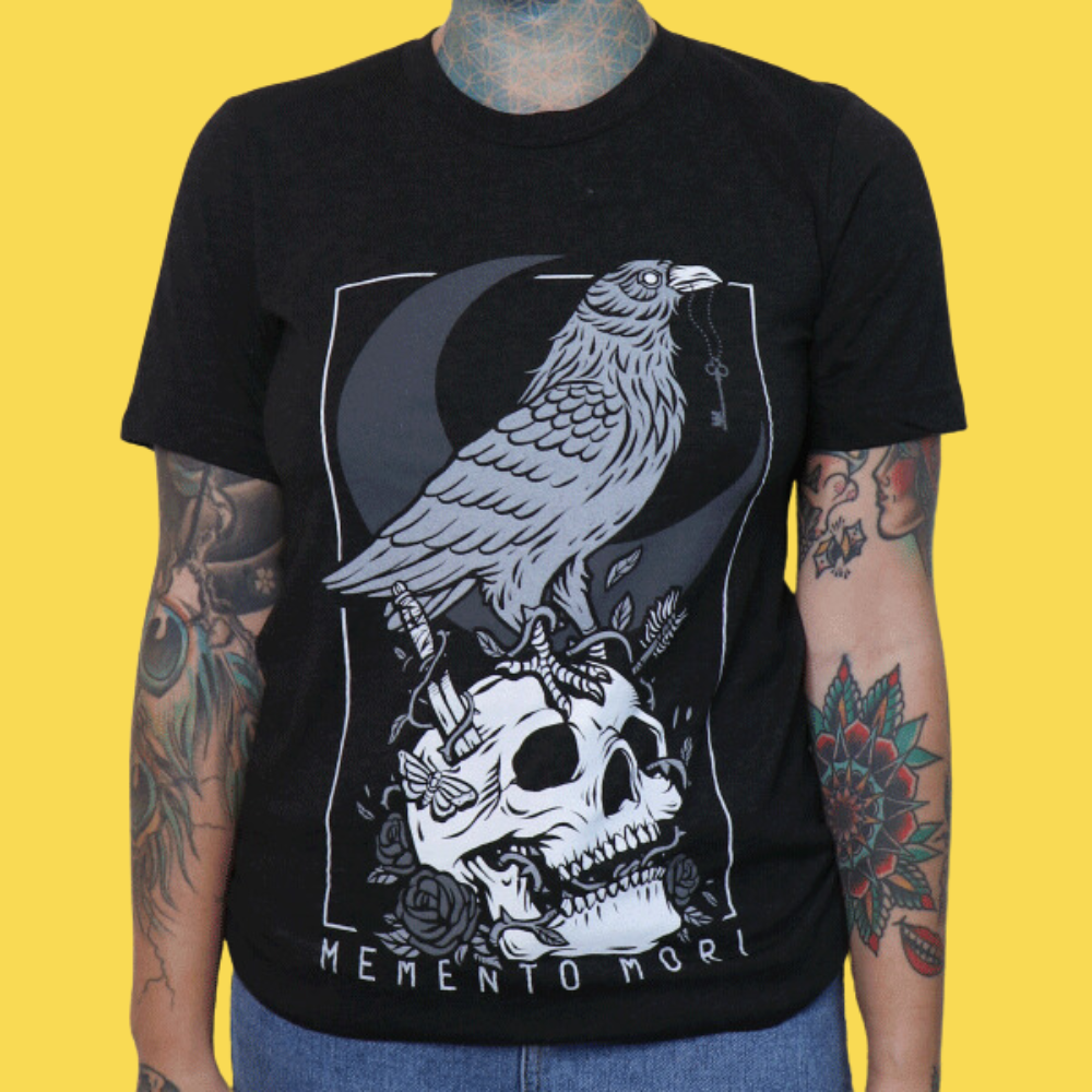 Black graphic tee featuring a raven perched on a skull with crescent moon and roses, 'Memento Mori' text below.