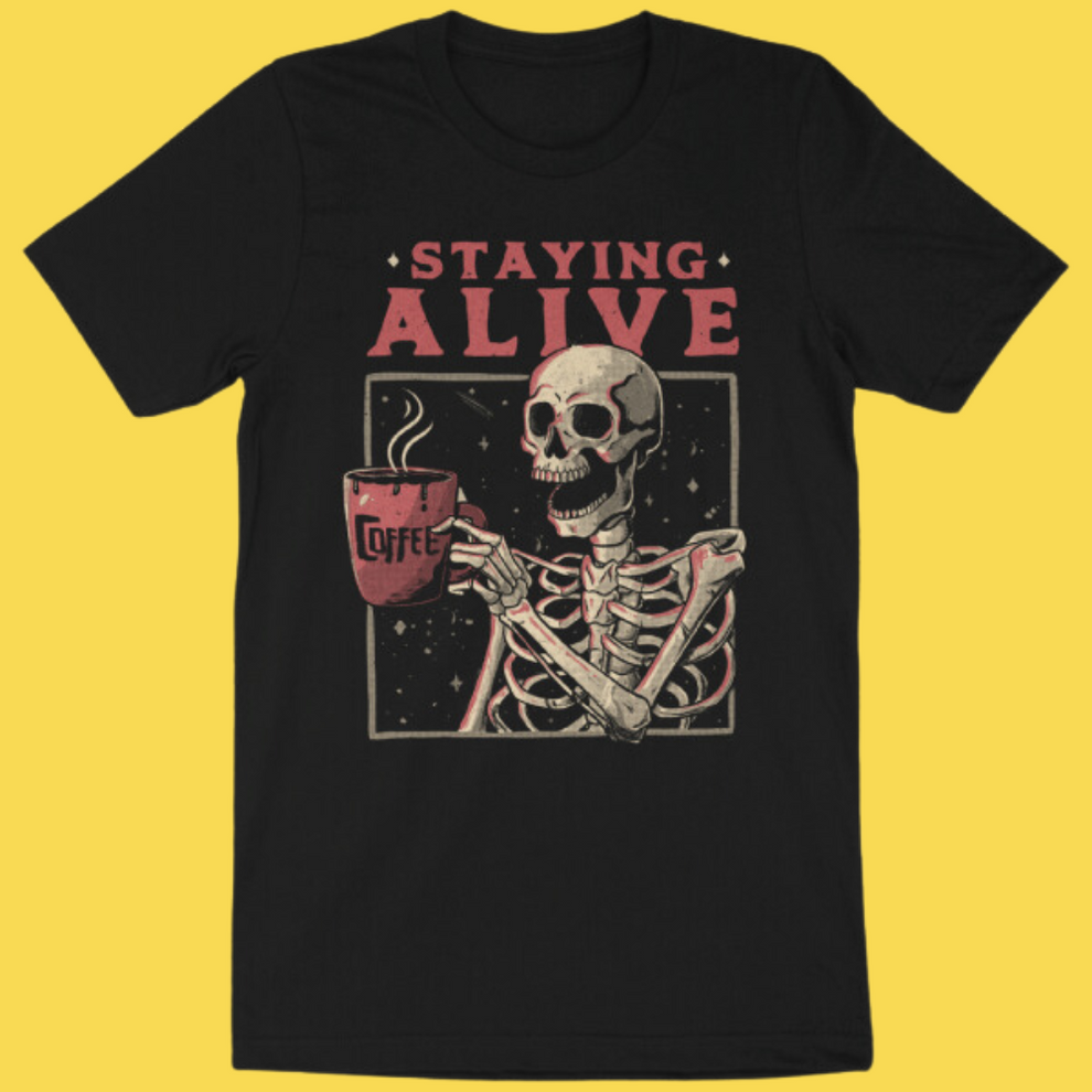 Black graphic tee featuring skeleton holding coffee mug with 'Staying Alive' text on yellow background