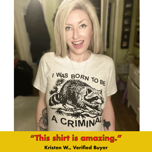 Black graphic tee with raccoon illustration and text 'I WAS BORN TO BE A CRIMINAL' in bold letters
