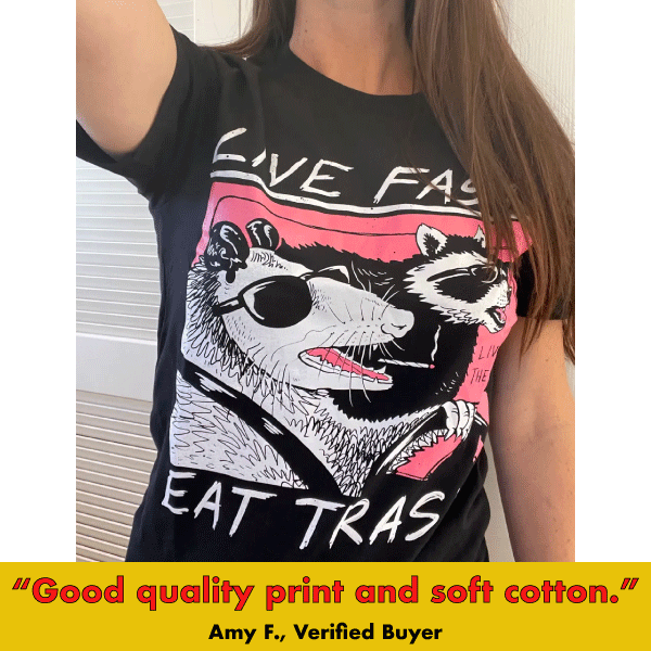 Black graphic tee with illustrated raccoon wearing sunglasses and 'Live Fast Eat Trash' text on pink and black design.