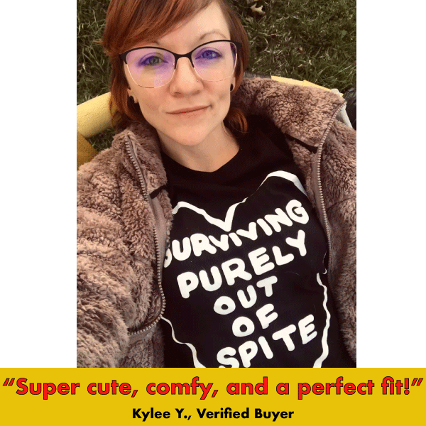 Black graphic tee with white text reading 'Surviving Purely Out Of Spite' worn with brown cardigan
