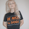 A woman wearing a black t-shirt with text that reads be nice to dogs