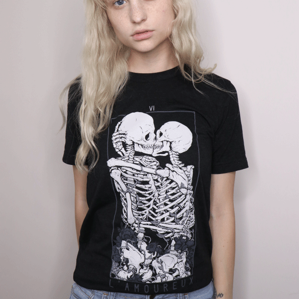 Black graphic tee featuring two skeletal figures kissing with 'The Lovers' text, gothic aesthetic on dark cotton shirt.