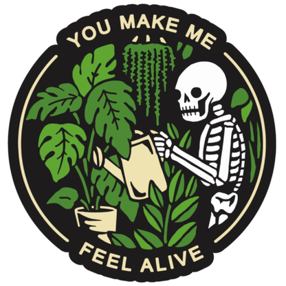 An enamel pin of a skeleton with a watering can surrounded by plants with text that reads you make me feel alive